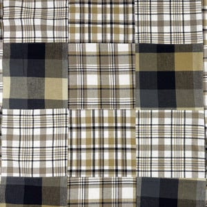 May include: A patchwork textile featuring a grid of squares with plaid patterns. The squares display a variety of colors, including white, black, and shades of brown and tan. The fabric has a rustic, homespun aesthetic.