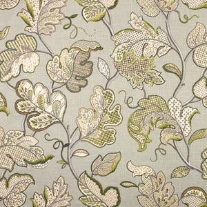 May include: A fabric with a repeating pattern of stylized leaves and vines in shades of green, cream, and brown against a pale gray background. The leaves have intricate embroidered details.