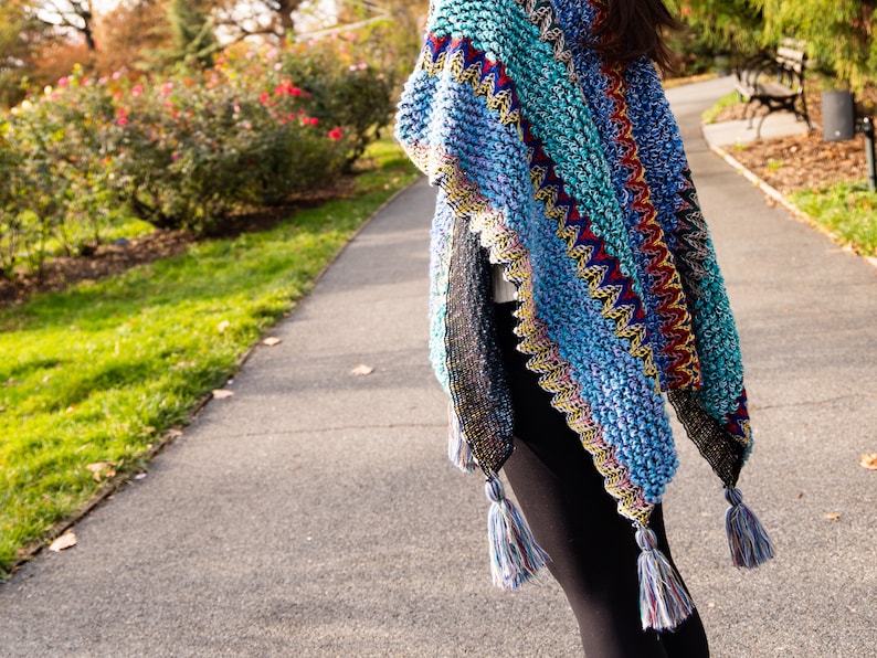 Puede incluir: Un chal de ganchillo colorido con un patr&oacute;n geom&eacute;trico y flecos. El chal est&aacute; hecho con una variedad de colores, incluyendo azul, verde, amarillo, rojo y negro.