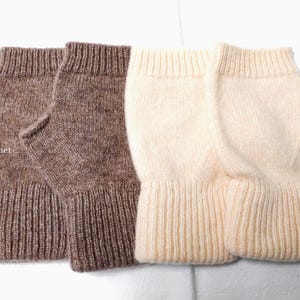 May include: Four knitted fingerless gloves in shades of brown and cream. The gloves have a ribbed cuff and a section for the fingers to extend. The brand name "TibiCrochet" is visible on the left side of the image.