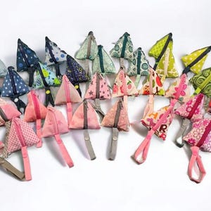 May include: A collection of 25 colorful triangular zippered pouches with various patterns and designs. The pouches have a strap attached to each one.