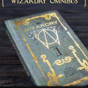 K&ouml;nnte beinhalten: Ein gr&uuml;nes gebundenes Buch mit dem Titel The Wizardry Omnibus Volume 1 mit goldener Folienpr&auml;gung und verzierten Filigranmustern auf dem Einband. Der Buchr&uuml;cken zeigt ebenfalls den Titel in Gold. Die Website ArchiveOfWizardry.com steht unten.