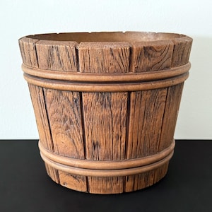 May include: A brown ceramic planter shaped like a wooden barrel with a textured surface.