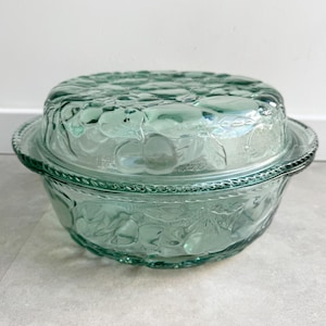 Peut inclure: Un plat à four rond en verre vert clair avec un couvercle assorti. L'extérieur du bol et du couvercle présente un motif en relief texturé représentant divers fruits. Le bord du bol est orné d'un motif en relief en forme de corde.