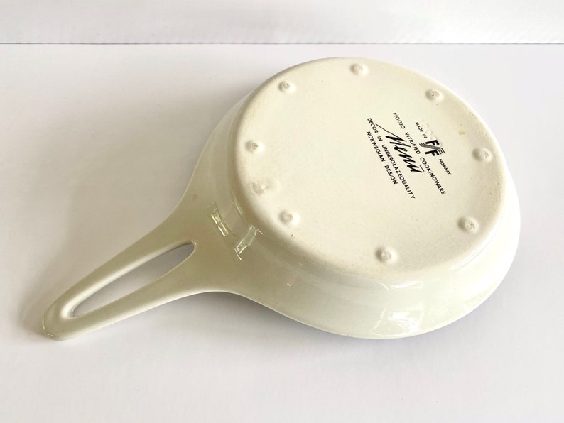 Pu&ograve; includere: Padella in ceramica bianca con manico nero e il testo "Menu" in lettere nere. La padella &egrave; contrassegnata con "Food Vitrified Cookware" e "Decor in Undersalability Norwegian Design".