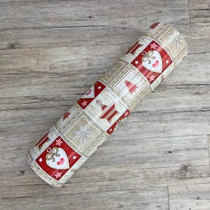 Könnte beinhalten: Eine Rolle braunes und weißes Geschenkpapier mit einem roten und weißen Weihnachtsmotiv. Das Design zeigt Herzen, Sterne und Weihnachtsbäume.