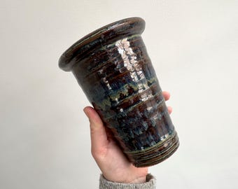 Könnte beinhalten: Eine braune und blaue Keramikvase mit einer breiten Öffnung und einem schmalen Boden. Die Vase hat eine gefleckte Glasur mit braunen, blauen und grünen Streifen.