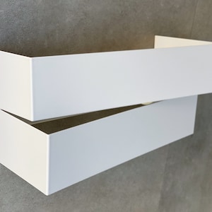 Peut inclure: Deux boîtes rectangulaires blanches empilées l'une sur l'autre. La boîte du haut est légèrement ouverte, révélant la boîte du bas.