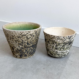 May include: Two ceramic planters with a speckled white and green glaze. The larger planter has a green interior.