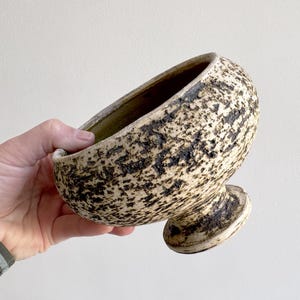 Könnte beinhalten: Ein Set aus drei Keramikbechern mit gesprenkelter, matter Oberfläche. Die Becher sind in Creme-, Hellgrau- und Dunkelgrautönen gehalten. Jeder Becher hat ein schlichtes, minimalistisches Design, perfekt für Kaffee oder Tee.