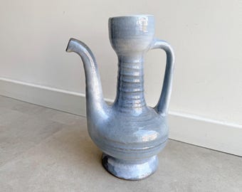 May include: A light blue ceramic pitcher with a long spout and a handle. The pitcher has a bulbous base and a cylindrical neck. The overall height is approximately 12 inches.