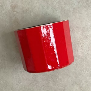 Könnte beinhalten: Ein roter achteckiger Keramik-Pflanztopf mit glänzender Oberfläche.