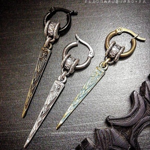 Pode incluir: Três brincos de argola de prata e ouro com um design pontiagudo e texturado. Os brincos têm um aro de prata com uma conta decorativa e um pingente pontiagudo de prata ou ouro.