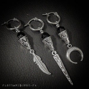 May include: Three silver earrings with black gemstone accents. Each earring features a different design: a feather, a crescent moon, and a geometric shape.