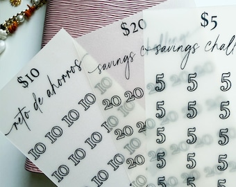 May include: Three translucent vellum sheets featuring savings challenge trackers with black printed text. The sheets display dollar amounts of 5, 10, and 20, with corresponding numerical icons for tracking progress. The text includes savings challenge and reto de ahorros.