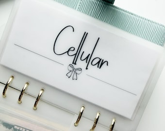May include: A white plastic envelope with the word "Cellular" in black script, a bow graphic, and a horizontal line. The envelope is part of a binder with gold rings and a light green cover.