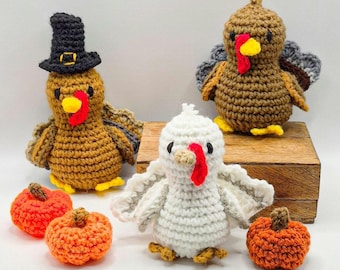 May include: Three crocheted turkey figures and three small crocheted pumpkins. One turkey wears a black top hat, one is brown, and one is white. Each turkey has a yellow beak and a red wattle. The pumpkins are orange with brown stems.