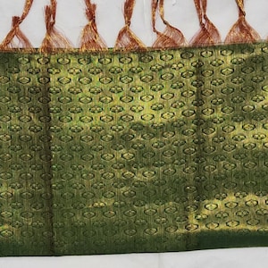 May include: A green and gold fabric border with a repeating pattern of small circles. The border has a fringe of red and gold threads.