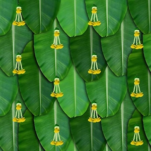 May include: A wall decorated with green banana leaves and yellow floral garlands. The garlands are hanging from the leaves and are arranged in a repeating pattern.