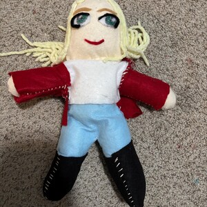May include: Handmade felt doll with blonde hair, a red jacket, a white shirt, blue pants, and black boots.