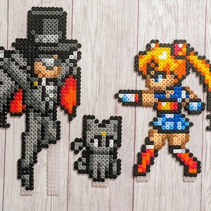 Könnte beinhalten: Ein Set aus drei Pixel-Art-Figuren aus bunten Perlen. Die Figuren sind ein schwarz gekleideter Charakter mit Zylinder, eine Katze und ein Mädchen mit blonden Haaren und einem blauen Kleid.