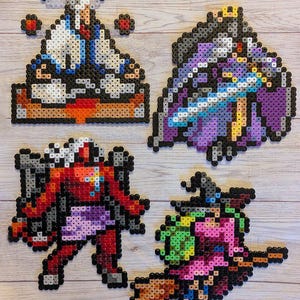 May include: Four pixel art characters created using colourful beads. The characters are a white-haired man in a blue and white robe, a purple-robed figure with a sword, a red-skinned figure with a purple skirt, and a witch with a green hat and a broom.