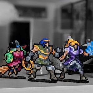 May include: Four pixel art figures made of colourful beads. The figures are standing on black bases. The figures are a blue and green wizard, a purple and blue warrior, a green and yellow warrior, and a red and green warrior.
