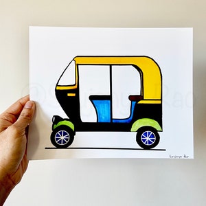 May include: A colorful illustration of an auto rickshaw, featuring a yellow roof, black body, and blue and green accents. The artwork is on white paper and held by a hand.