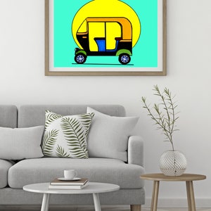 May include: A framed art print featuring a colorful illustration of an auto rickshaw, or tuk-tuk, against a bright yellow sun and a turquoise background. The vehicle is black, yellow, and blue, with green wheels. The artwork is displayed in a light brown wooden frame.