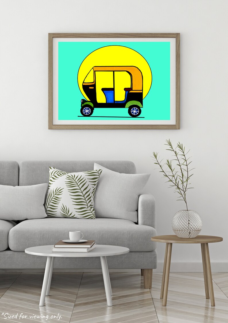 May include: A framed art print featuring a colorful illustration of an auto rickshaw, or tuk-tuk, against a bright yellow sun and a turquoise background. The vehicle is black, yellow, and blue, with green wheels. The artwork is displayed in a light brown wooden frame.