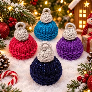 May include: Four round, hand-knitted Christmas baubles in red, blue, purple, and dark navy blue with silver glitter. Each bauble features a textured, ribbed knit pattern and a small, light grey crocheted cap with a loop for hanging.