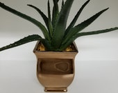 Large faux Aloe plant in copper painted ceramic container with small tan rocks glued in.