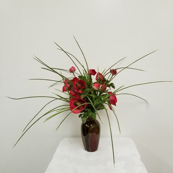 Faux Red Hellebores natural touch flowers, with faux onion grass and potted in a red and brown glazed ceramic bud vase.