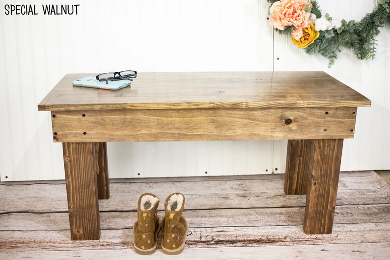 May include: A wooden bench with a natural stain finish. The bench has a simple design with four legs and a flat top. The bench is sitting on a wooden floor. The text "SPECIAL WALNUT" is visible in the top left corner of the image.