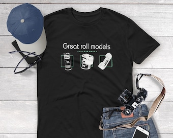 May include: Black t-shirt with the text "Great roll models" and three images of film canisters. The canisters are labeled "Kodak Max", "Porta Movie", and "Kodak", respectively.