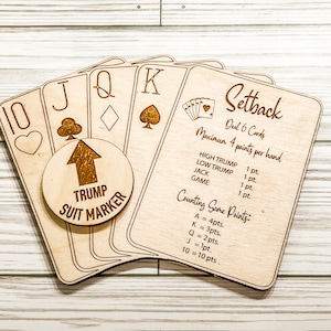 May include: Wooden game set for the card game Setback. The set includes a trump suit marker, a set of playing cards, and instructions for playing the game. The instructions include the number of cards to deal, the maximum points per hand, and the point values for each card.