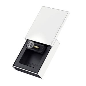 May include: A white ring box with a black interior. The box is open and a diamond ring is inside. The ring is set in a silver band and has a halo of smaller diamonds around the center stone. The box has the word "MONOLII" printed on the inside.