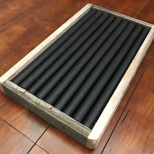 May include: A wooden ring holder with a rustic finish. The holder has a black felt lining with multiple slots for rings.