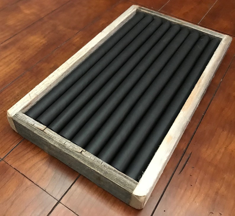 May include: A wooden ring holder with a rustic finish. The holder has a black felt lining with multiple slots for rings.