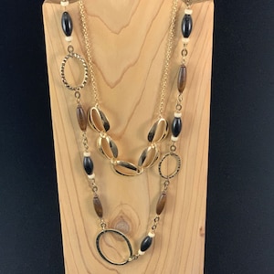May include: A layered necklace with gold oval and circle links and brown and black wooden beads.