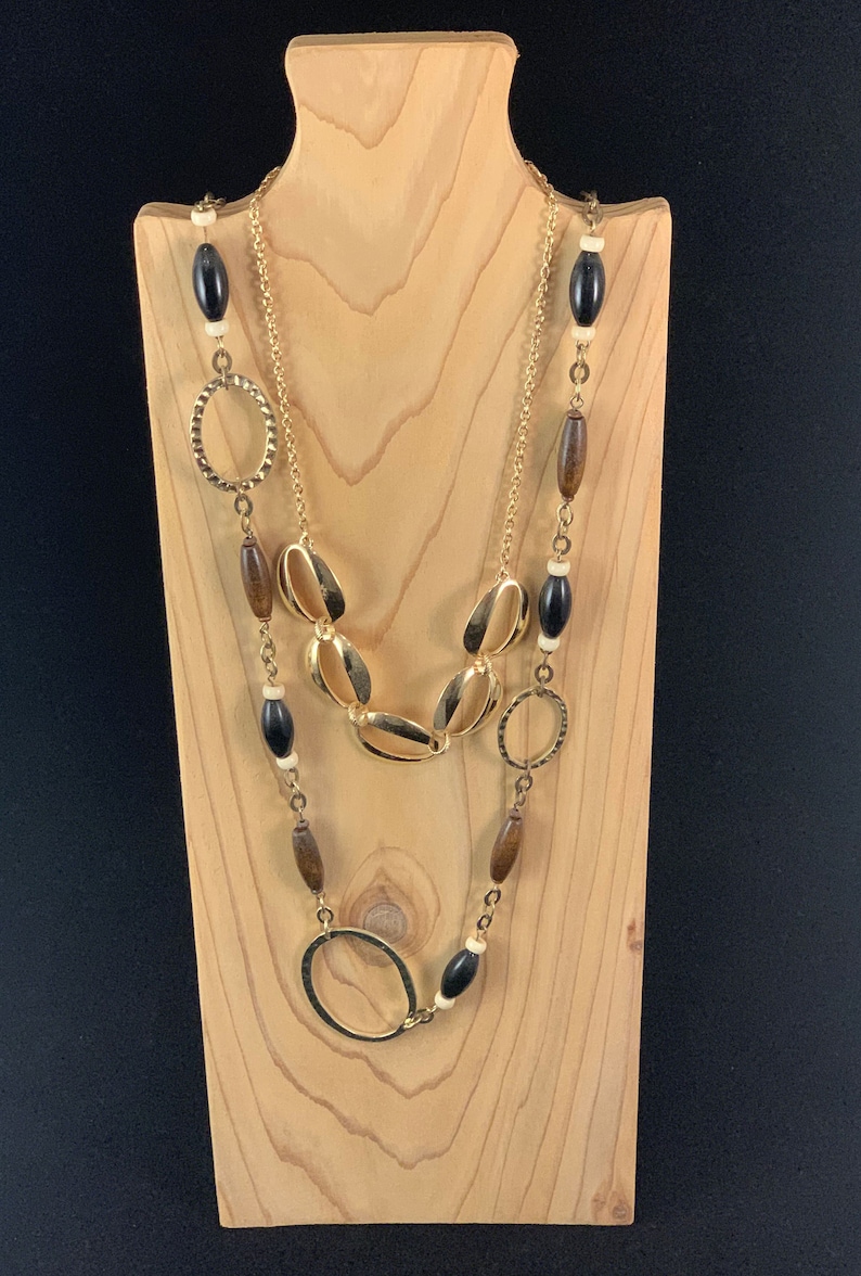 May include: A layered necklace with gold oval and circle links and brown and black wooden beads.