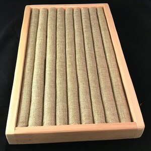 May include: A wooden ring display box with a beige fabric interior. The box has 10 slots for storing rings.