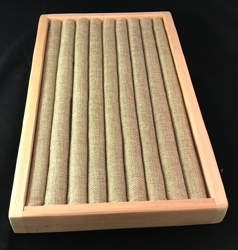 May include: A wooden ring display box with a beige fabric interior. The box has 10 slots for storing rings.