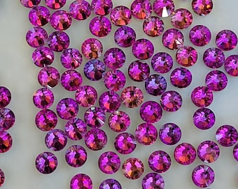 May include: A large quantity of small, round, iridescent pink rhinestones. The rhinestones have a faceted, reflective surface.