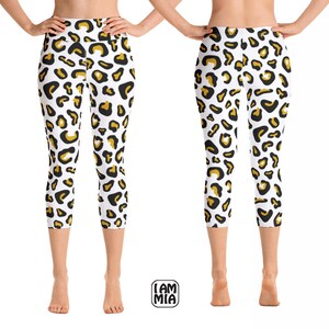 Könnte beinhalten: Weiße Yoga-Leggings mit einem Leopardenmuster in Schwarz und Gold. Die Leggings sind cropped und haben einen hohen Bund.