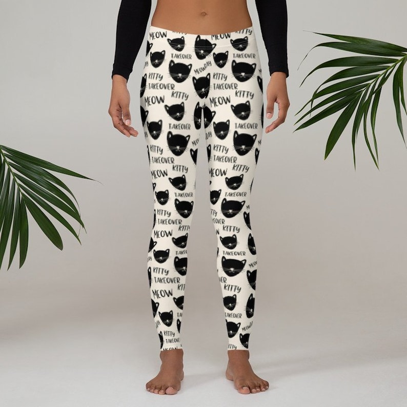 May include: Black and white leggings with a repeating pattern of black cat faces and the text "Kitty Takeover Meow".