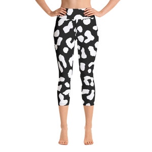 May include: Black and white capri leggings with a repeating pattern of white irregular shapes on a black background. The leggings are high-waisted and made of a stretchy material. The capri length ends just below the knees.