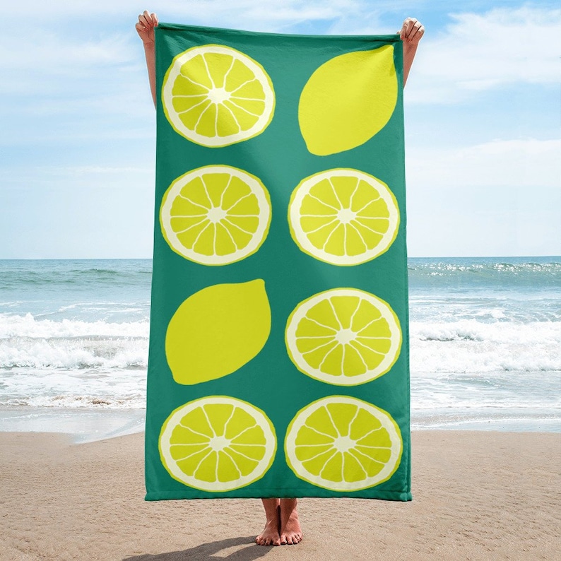 May include: A green beach towel with a lemon pattern. The towel features yellow lemons and lemon slices on a teal background.