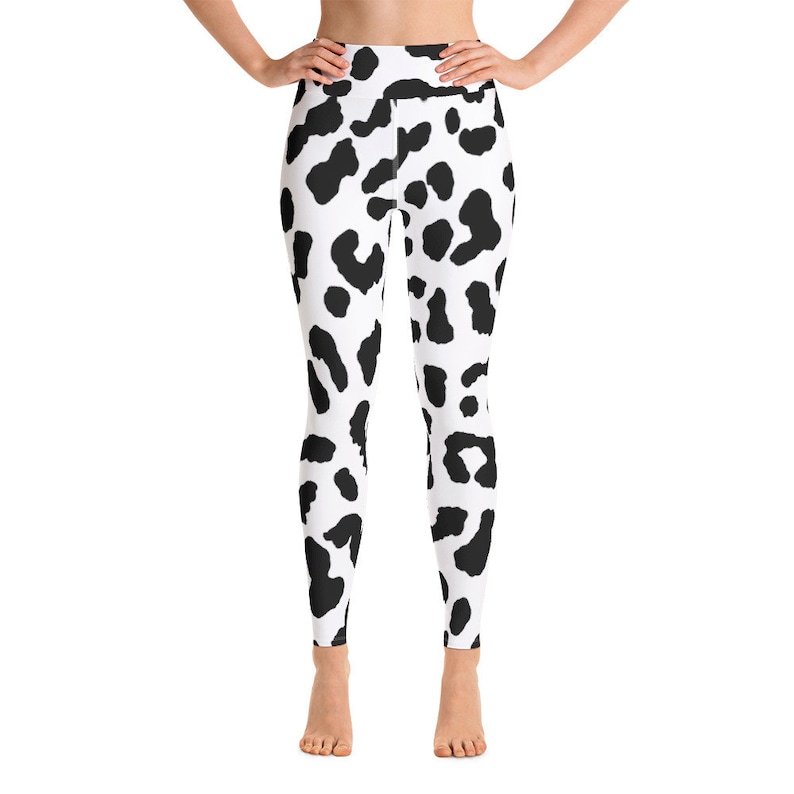 May include: High-waisted leggings with a white background and a black cow-like spot pattern. The leggings are form-fitting and reach the ankles. The fabric appears to be smooth and stretchy, suitable for athletic activities or casual wear.