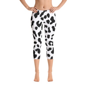 May include: Cropped leggings featuring a black and white dalmatian spot pattern. The leggings are mid-calf length and made of a stretchy material. The high-waisted leggings are suitable for various activities, including yoga and running.